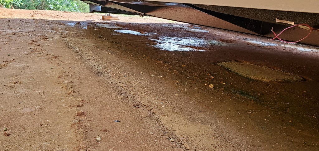 A look under the house showed water standing before the piers were set. Then after the house was lowered onto the piers the rainwater, mud and trash can be seen as wet as tears in the barrier. So water was seeping down into the red clay and rotting the grass. The problem had begun. 
